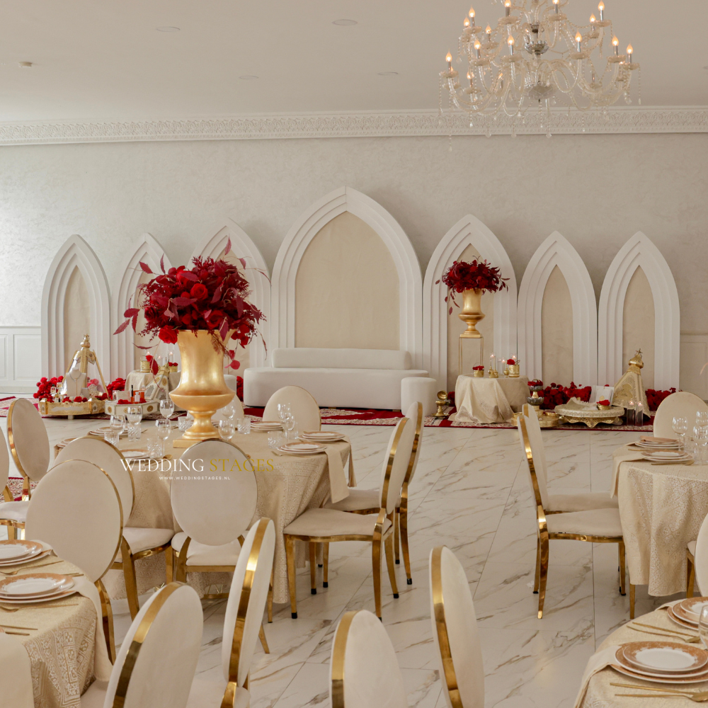 Elegante bruiloft zaal met witte en gouden decoratie.
