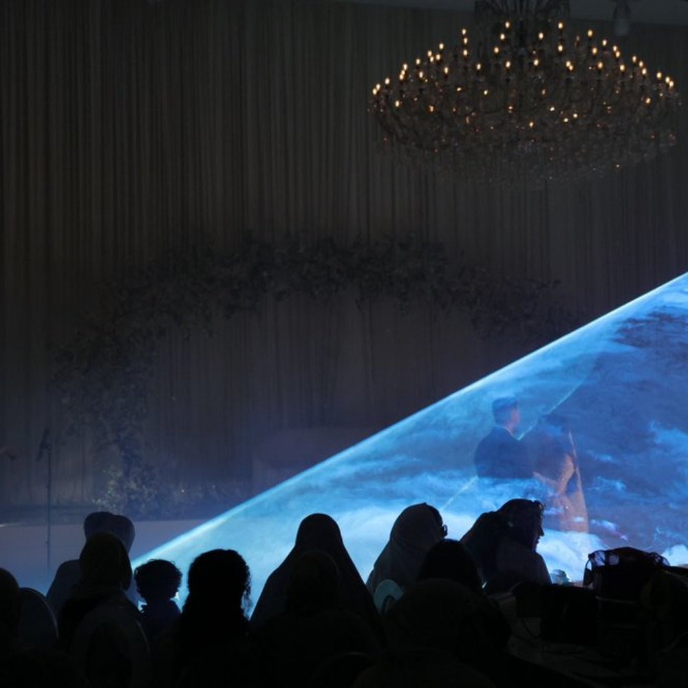 Laserprojectie op scherm tijdens evenement in donkere zaal.