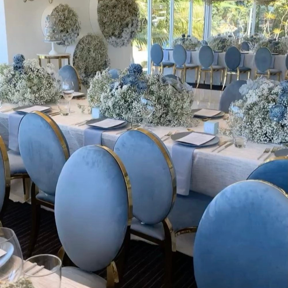 Elegante tafelsetting met blauwe stoelen en witte bloemen.