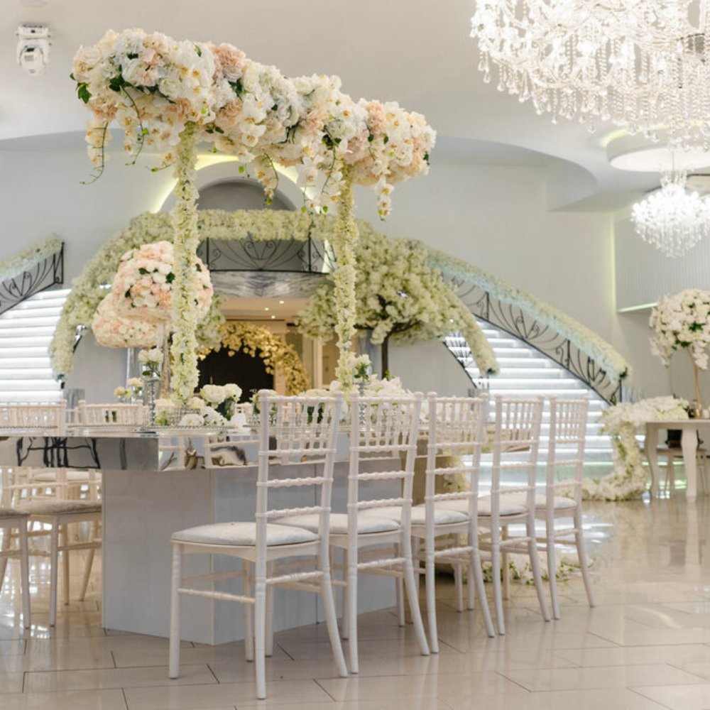 Elegante trouwzaal met bloemen en kristallen kroonluchters.