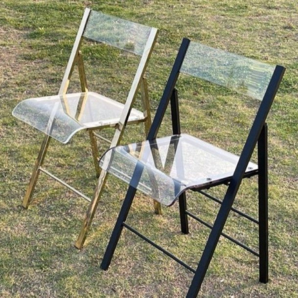 Twee doorzichtige klapstoelen op grasveld.