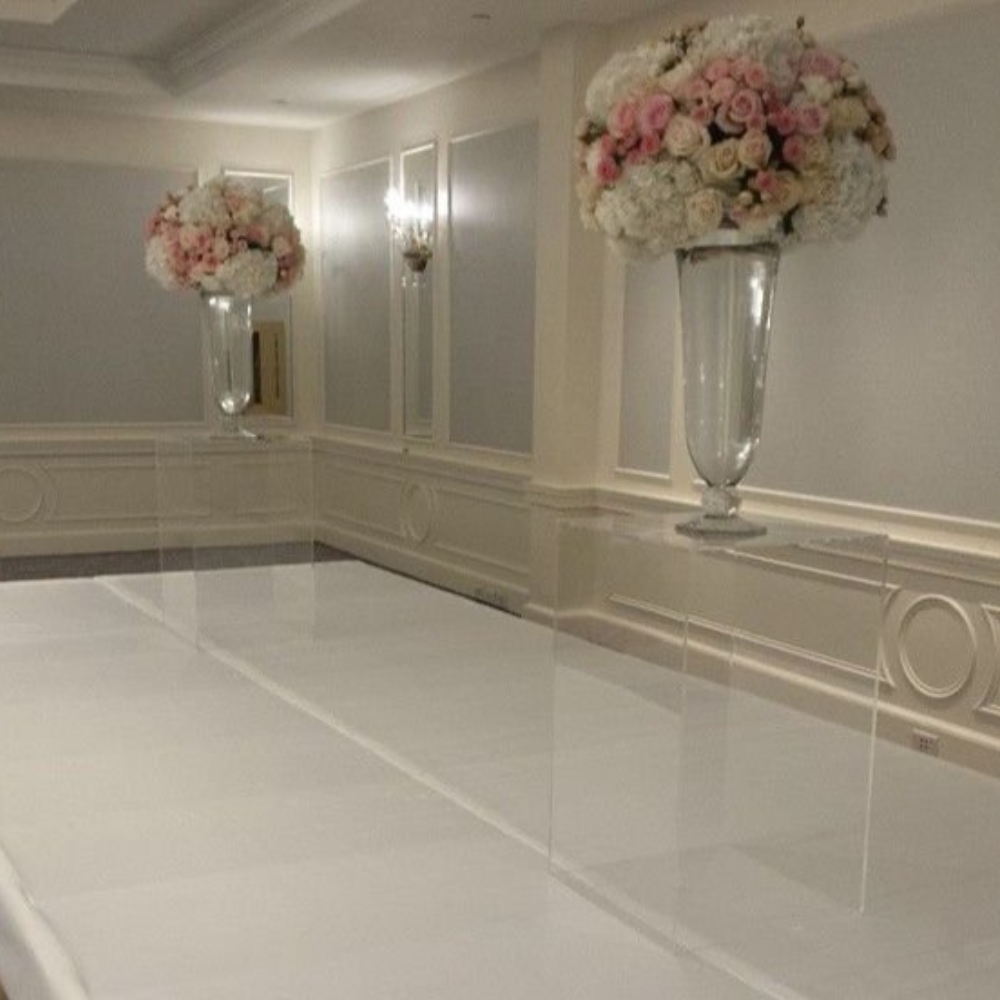 Bruiloftzaal met elegante bloemenarrangementen tegen witte wanden.