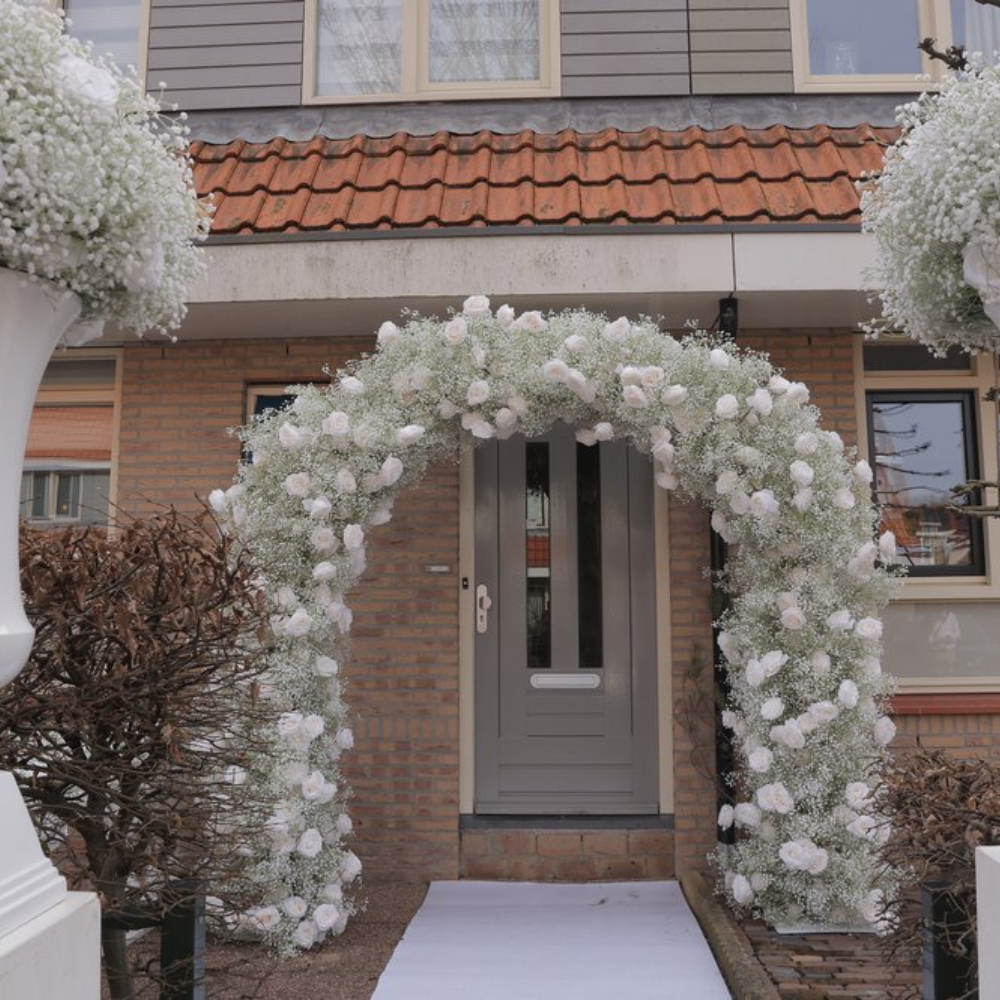 Bloemenboog bij voordeur van huis.