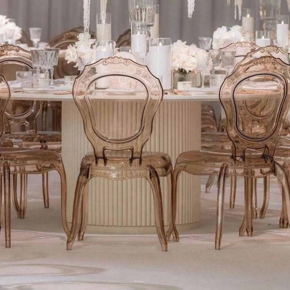 Elegante glazen stoelen rond gedekte tafel met bloemen
