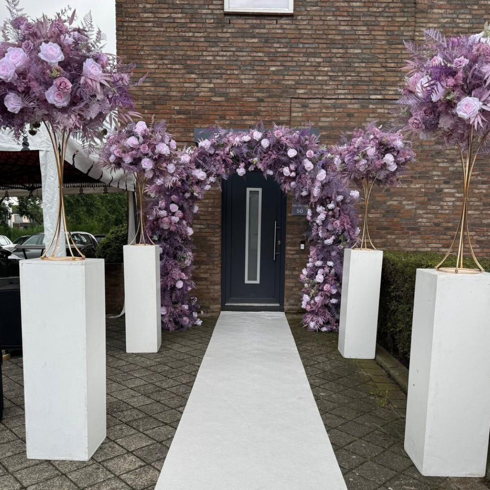 Bloemenboog met paarse rozen bij voordeur.