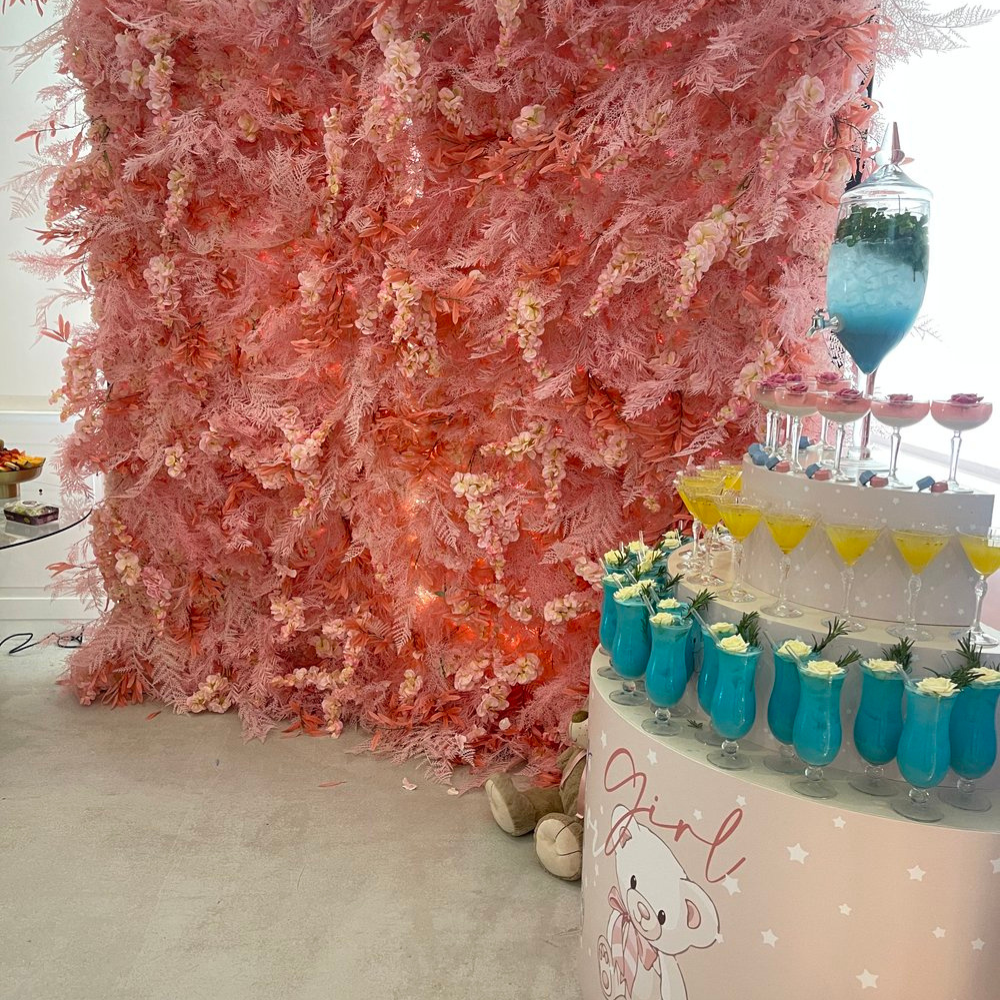 Roze bloemenmuur met kleurrijke feestdranken op tafel.