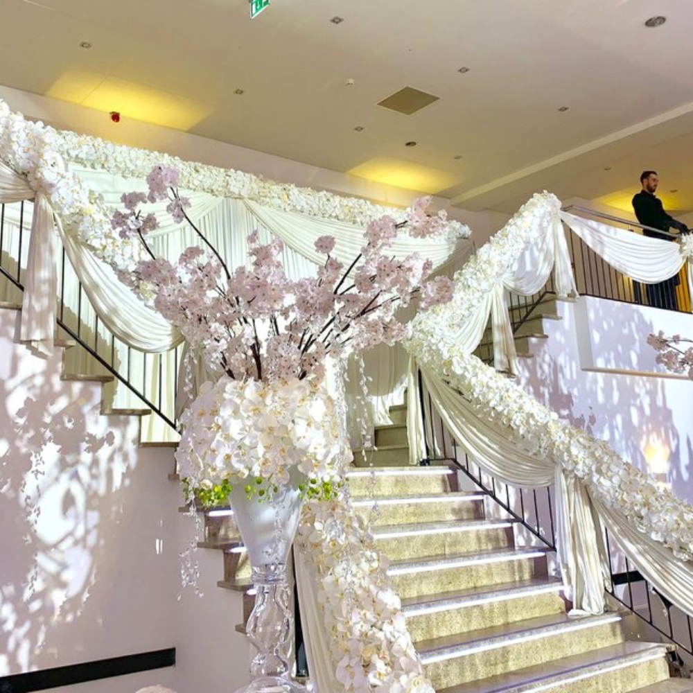 Versierde trap met bloemen en draperieën op bruiloft.