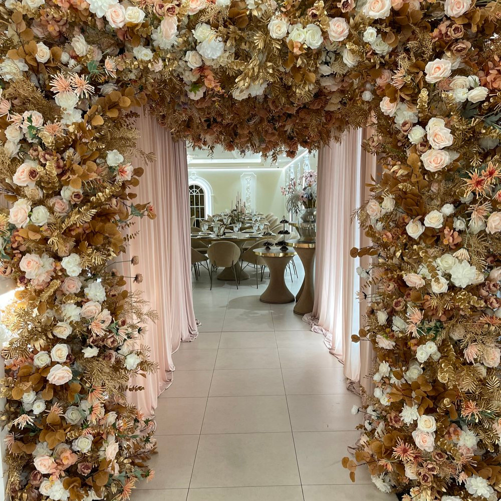 Bloemrijke boog naar elegante eetzaal met gedekte tafels.