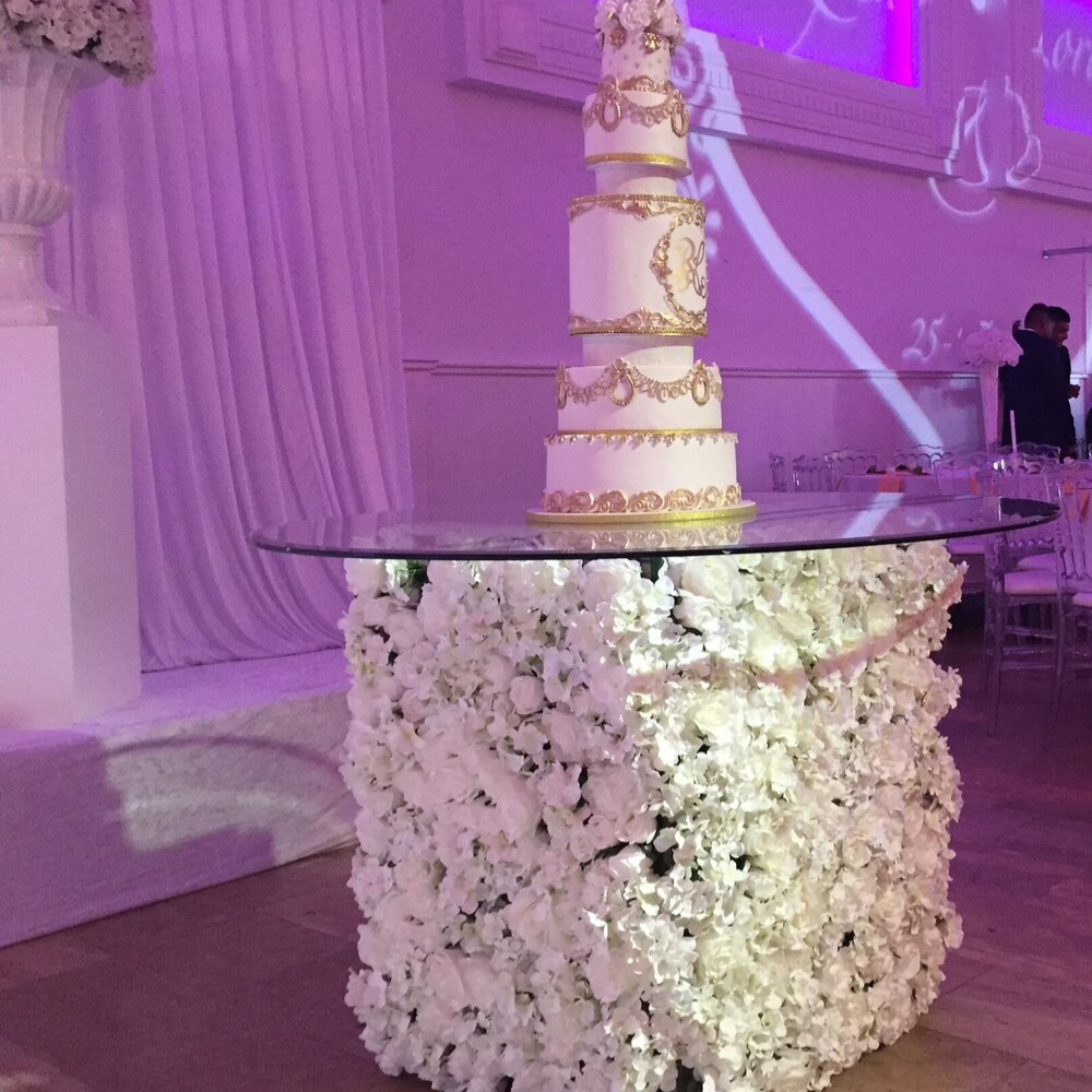 Hoge bruidstaart op bloemrijk tafel, elegante setting.
