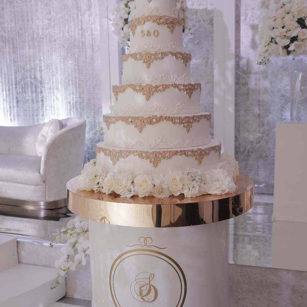 Vijflaags bruidstaart met gouden decoratie en bloemen
