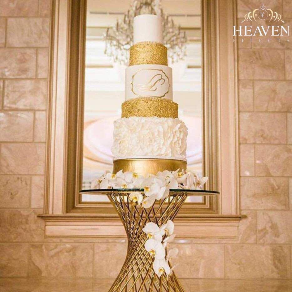 Luxe bruidstaart met gouden decoraties op elegante standaard.