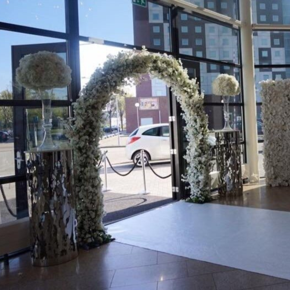 Witte bloemenboog voor bruiloftsdecoratie bij ingang.