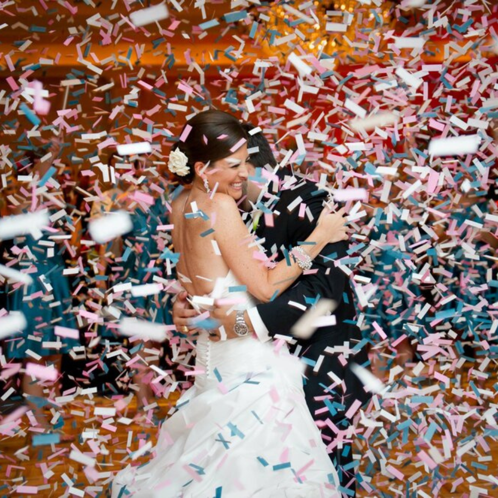 Bruiloftsdanspaar omringd door confetti.