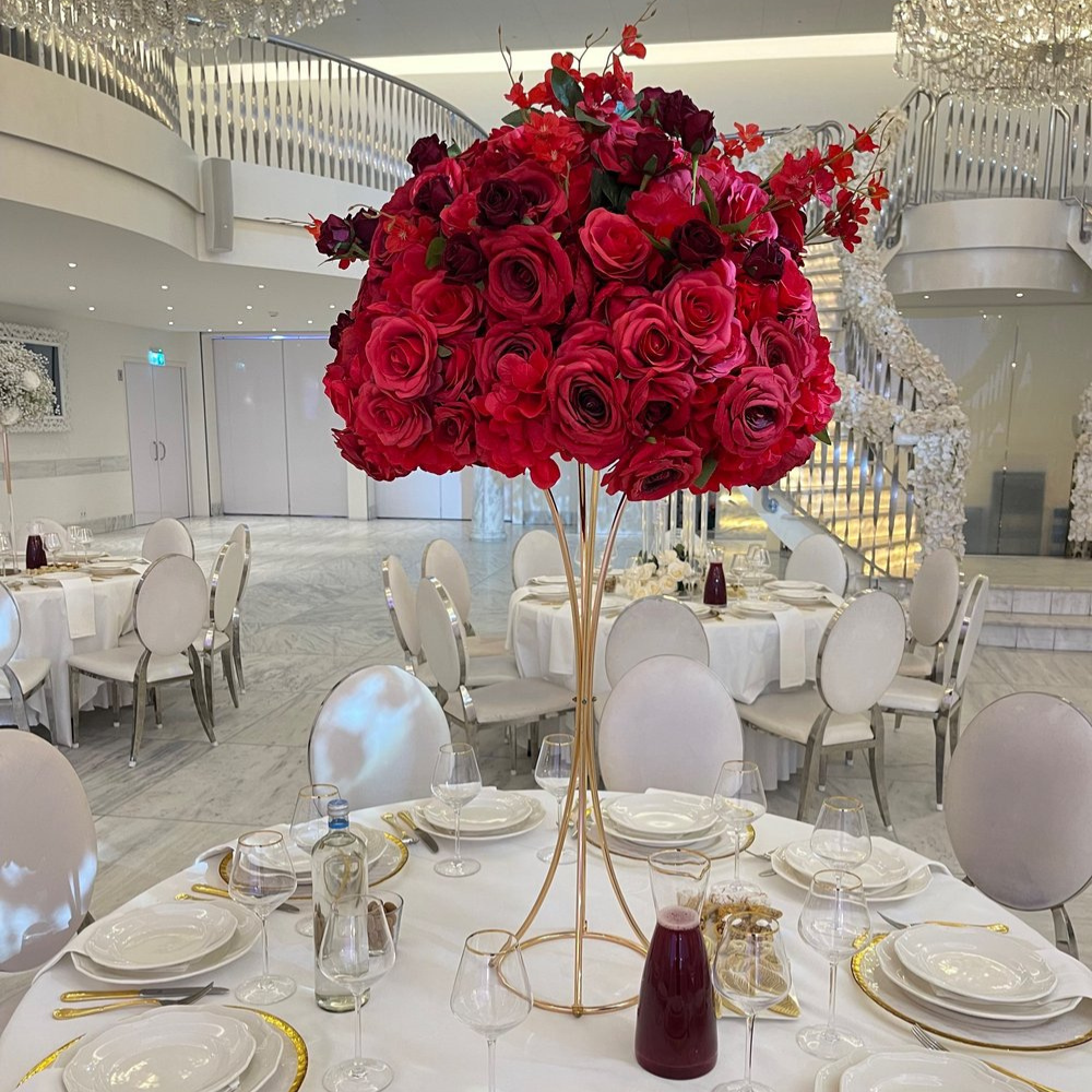 Luxe bruiloftzaal met rode bloemenarrangementen.