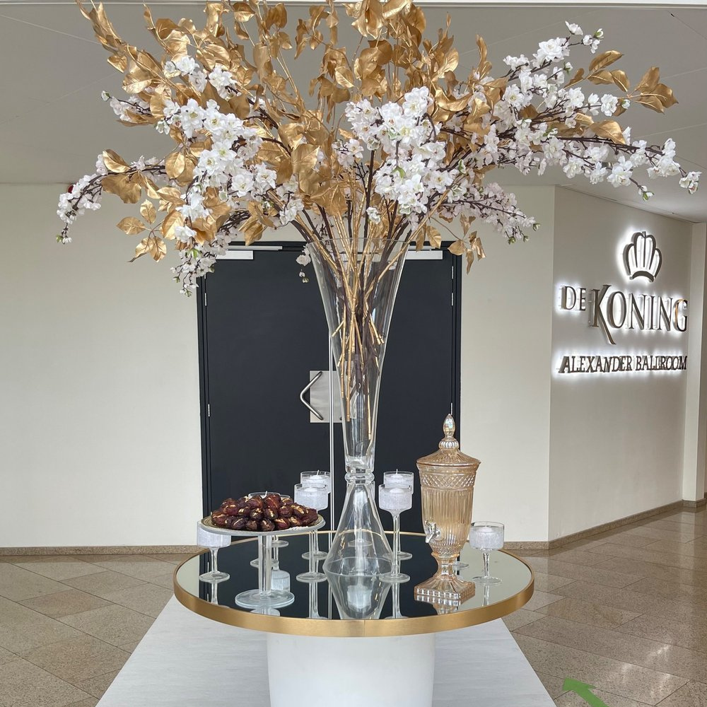 Elegante bloemenvaas met gouden bladeren in foyer.