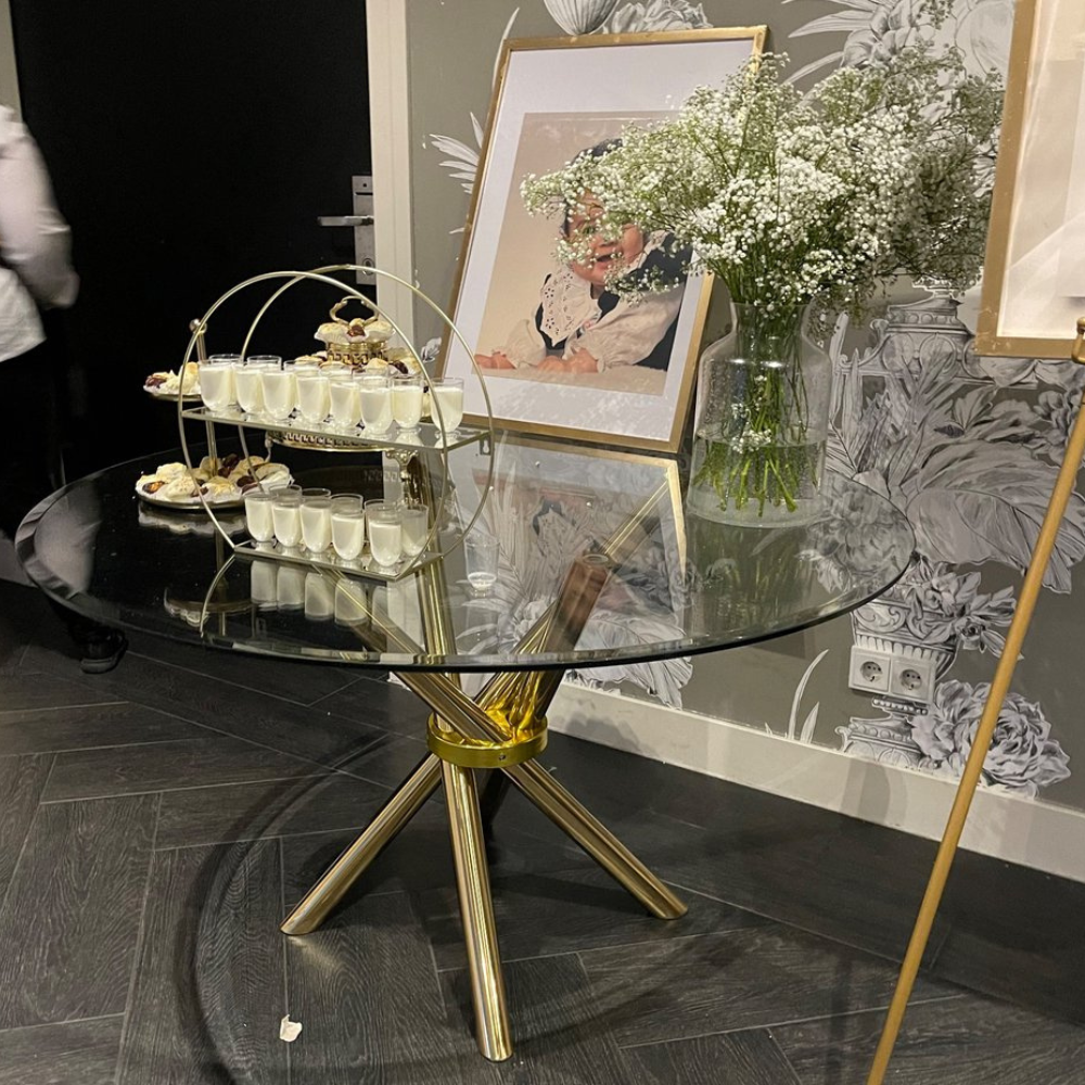 Glazen tafel met desserts en bloemen.