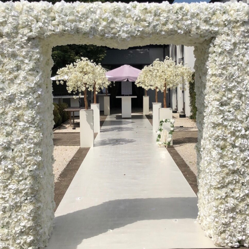 Bloemrijke trouwlocatie met witte rozen en bogen.