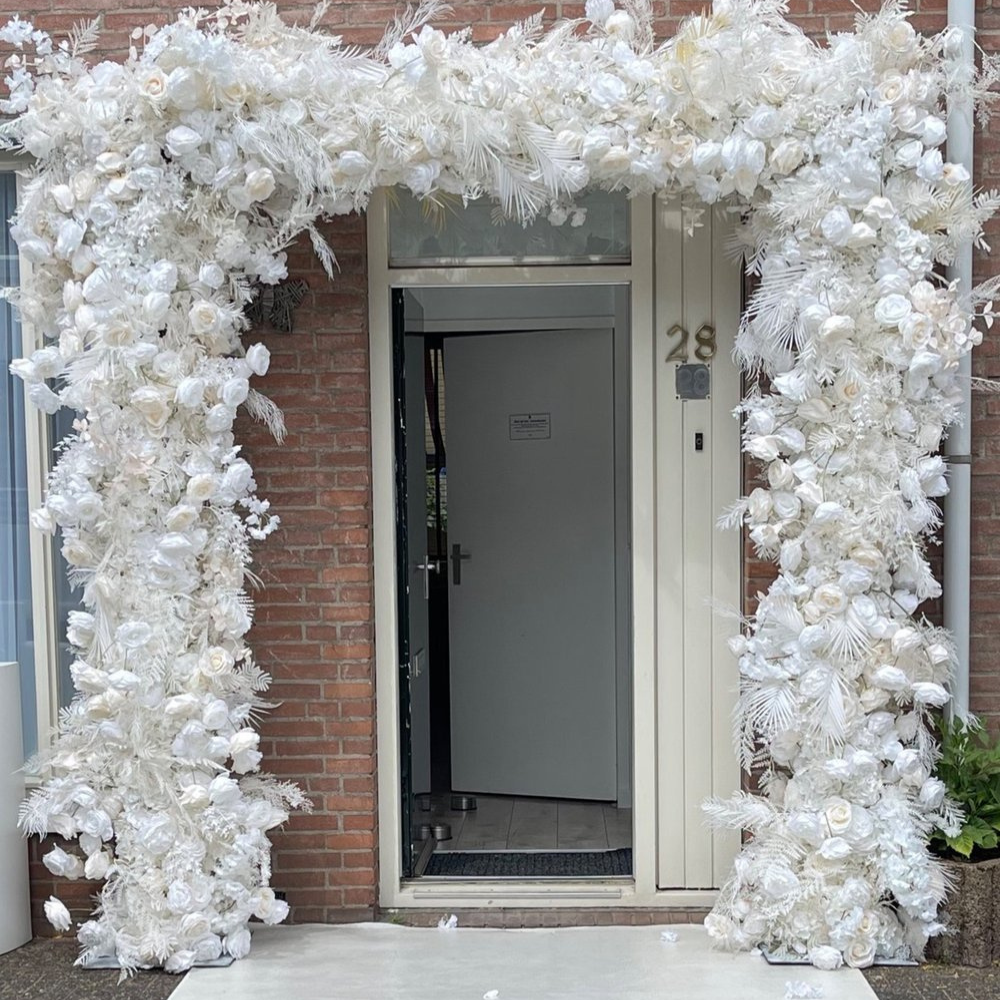 Ingang versierd met witte bloemen en bladeren.