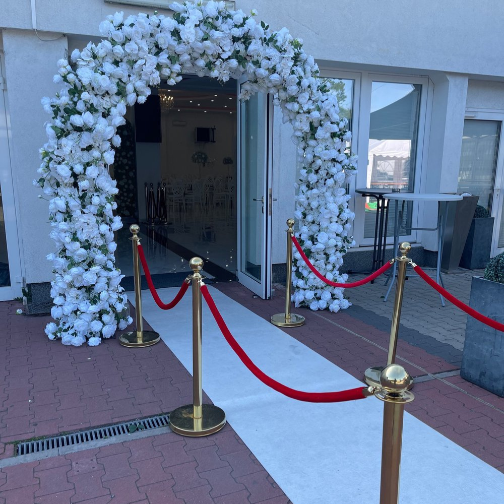 Bruiloft ingang met bloemenboog en rode loper