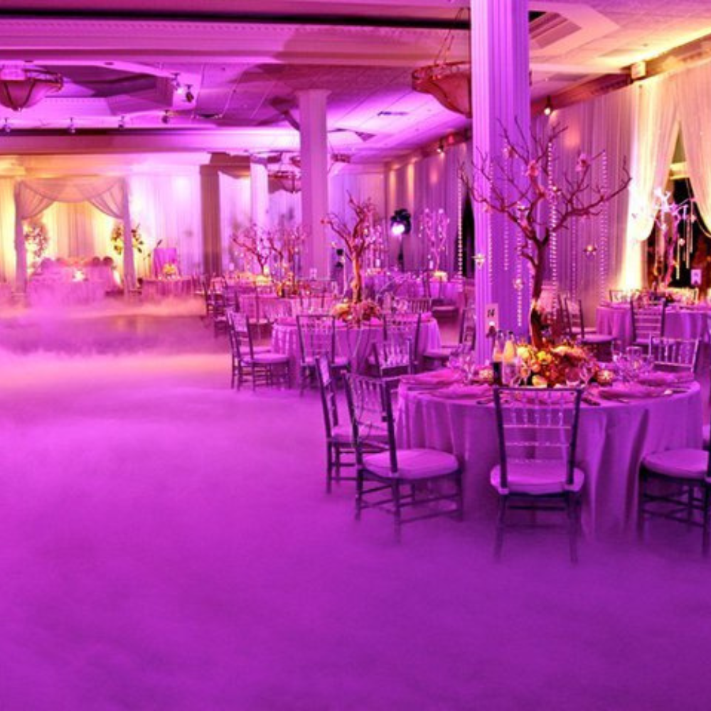 Sfeervolle paarse bruiloftszaal met bloemen en decoratie.