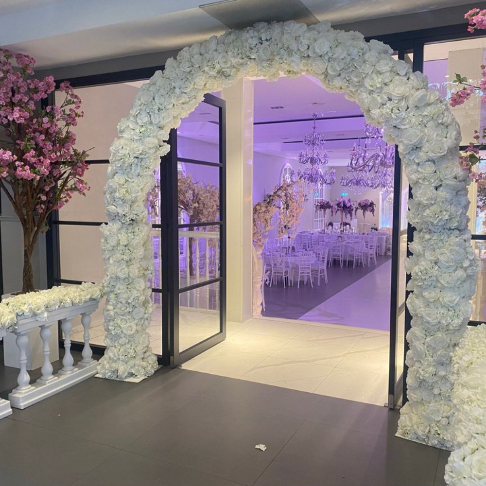 Witte bloemenslinger boog versiert ingang feestzaal.
