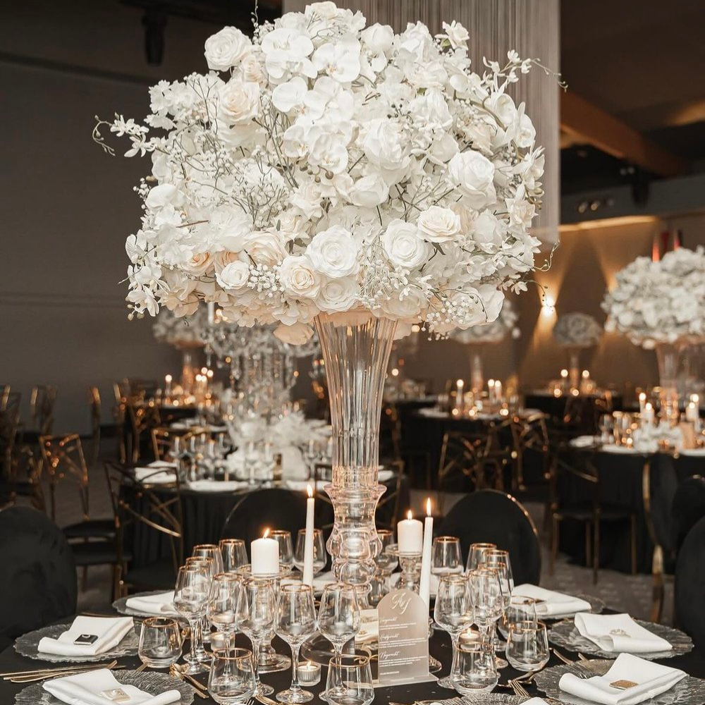 Elegante tafelsetting met witte bloemen en kaarsen.