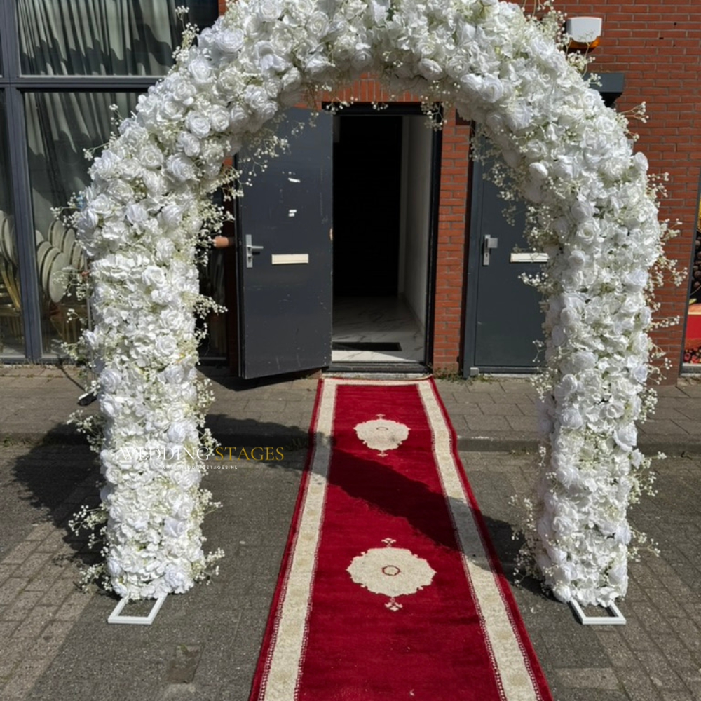 Bloemenboog met rode loper naar open deur.