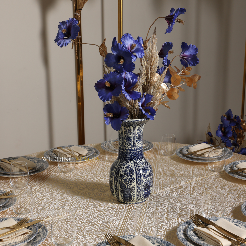 Gedekte tafel met bloemen in blauwe vaas.