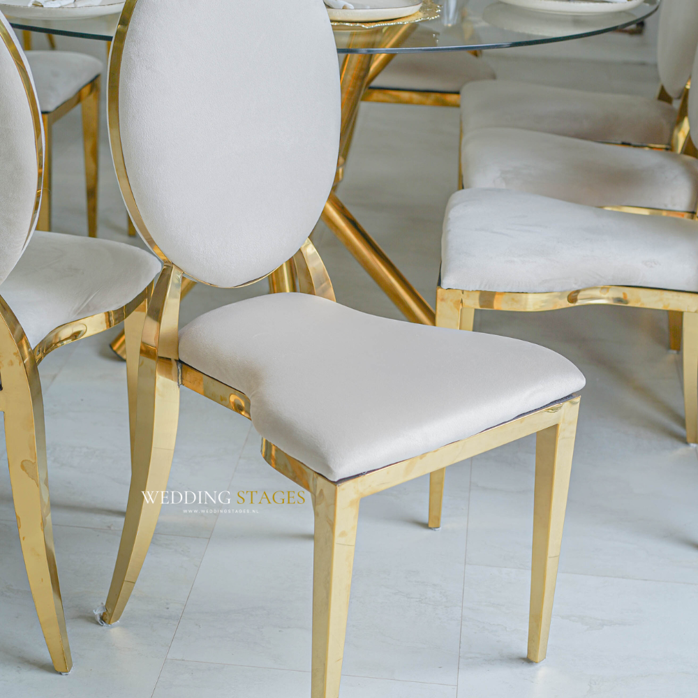 Gouden stoelen rondom glazen tafel, elegante inrichting.